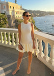 Shop PEGASI Aurora sleeveless off white ribbed knit mini dress online, styled on a scenic seaside terrace