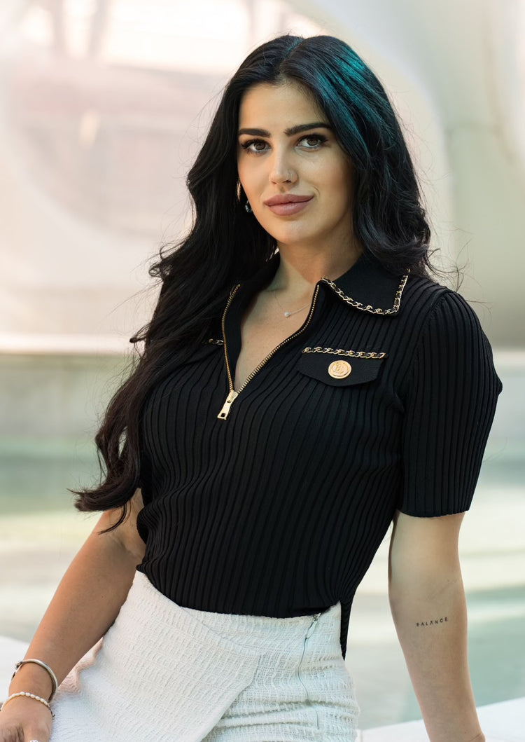 Close-up of the Casablanca black zip up knit polo shirt showing ribbed fabric and silver chain detail