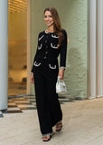 Woman in a black outfit with white accents standing in front of a building entrance.
