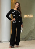 Woman in a black outfit with white accents standing in front of a luxe store.