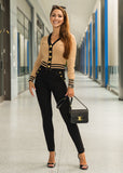 Woman in a stylish outfit with a beige cardigan and black pants, holding a handbag, in a modern hallway.