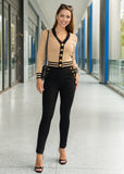 Woman in a beige cardigan and black pants standing in an indoor setting.