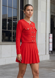 Back view of red knit cardigan and pleated mini skirt set showing fit and silhouette by shoppegasi.