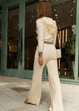 Woman in a beige outfit walking on a sidewalk with a store front in the background