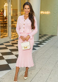 A delicate pink pointelle knit set featuring a high-waisted midi skirt and a lightweight cardigan for a chic and cozy look.