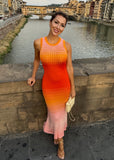 Woman in a colorful dress standing by a river with a bridge and buildings in the background