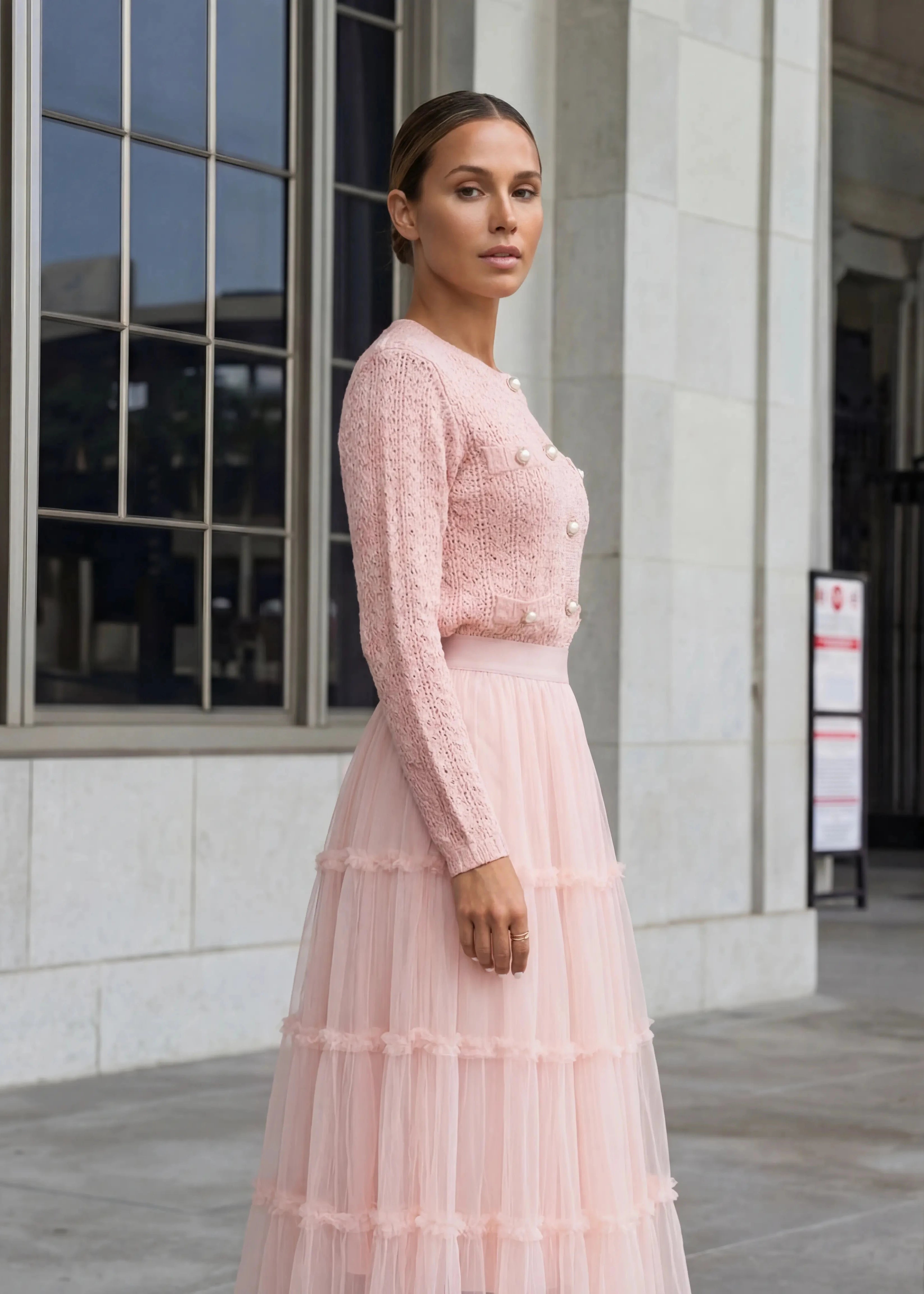 Elegant blush pink knit cardigan paired with tiered tulle maxi skirt featuring pearl buttons from shoppegasi.