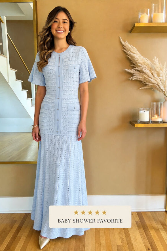 Woman in a light blue dress standing in a home setting with decorative elements.