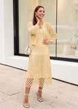 Model wearing buttery yellow ribbed knit midi dress styled for an elegant daytime look