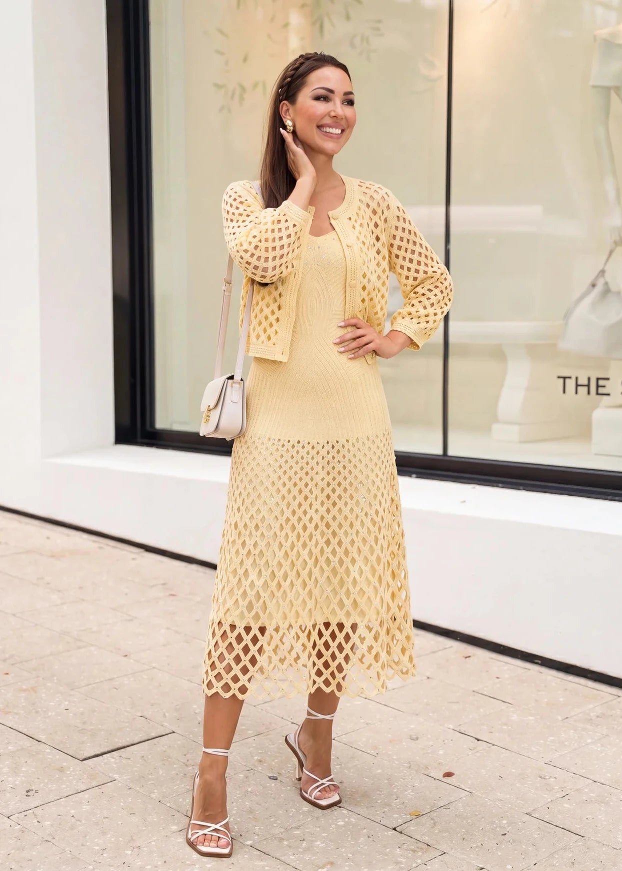 Close-up of open-knit cardigan hem in buttery yellow with textured pattern and embellishment detail