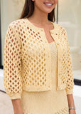 Model wearing buttery yellow open-knit cropped cardigan layered over knit dress