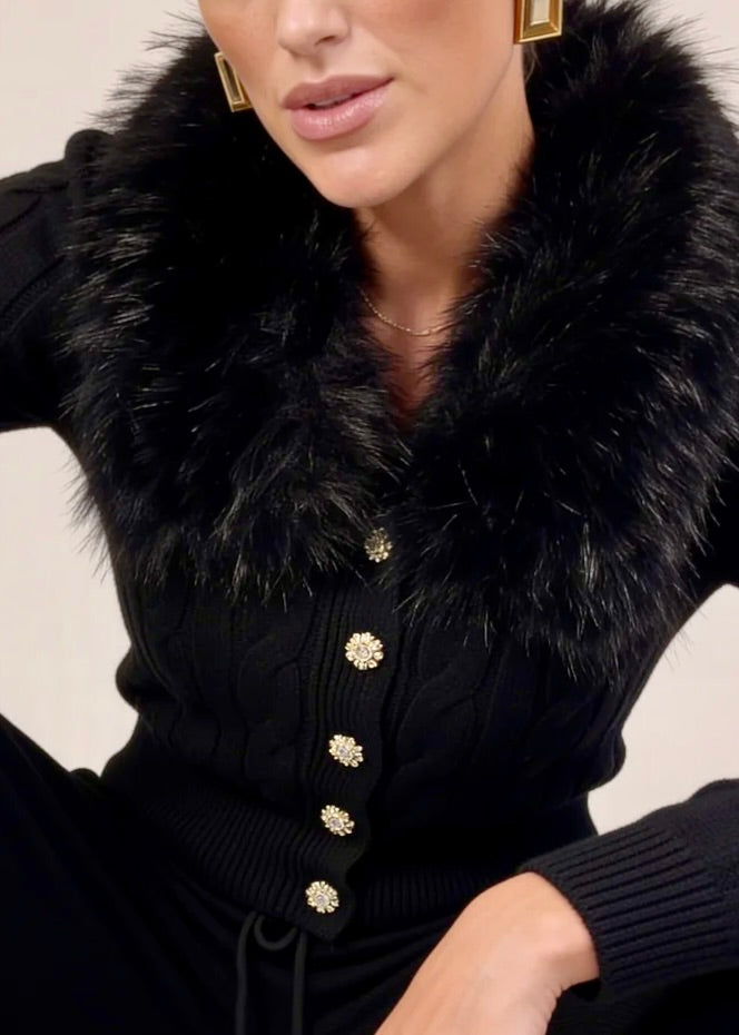 Close-up of faux fur collar and gold button detail on black knit cardigan