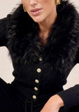 Close-up of faux fur collar and gold button detail on black knit cardigan