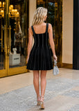 Woman wearing black contrast stitch flare knit mini dress photographed from the back outside a luxury boutique entrance with silver handbag and elegant heels.