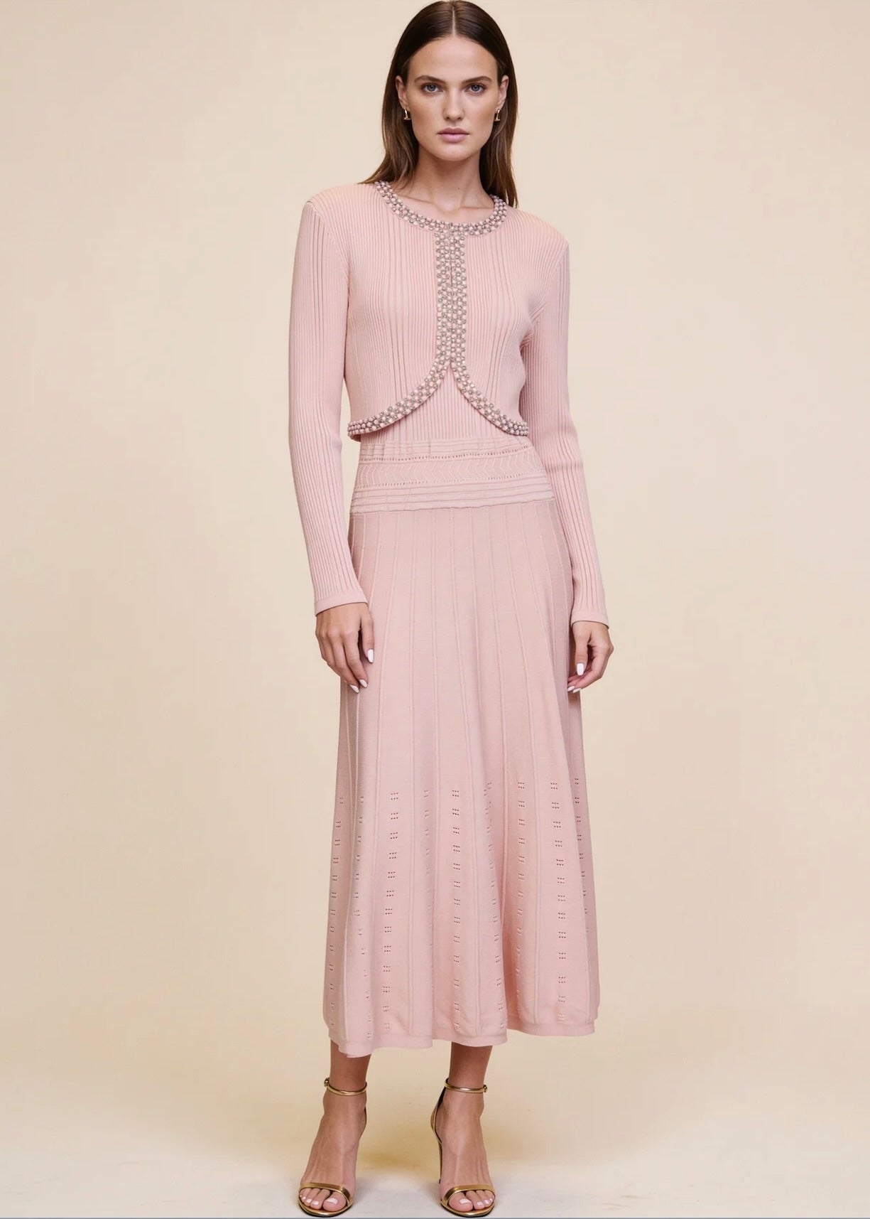Pink ribbed knit cardigan buttoned closed over pearl and crystal trim midi dress, full body
