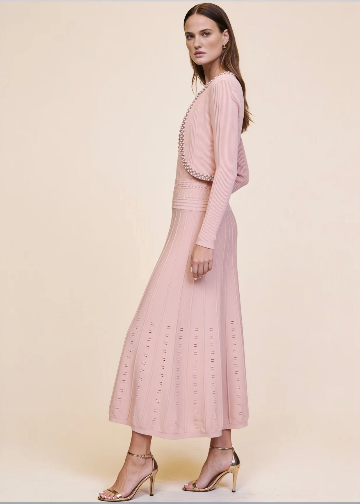 Side view of pink ribbed knit cardigan and pleated midi dress set with pearl and crystal trim, full body