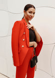 Red pantsuit featuring a double-breasted blazer with button details and structured fit, paired with straight-leg trousers for a sleek silhouette.