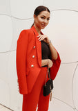 Red pantsuit featuring a double-breasted blazer with button details and structured fit, paired with straight-leg trousers for a sleek silhouette.