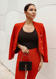 Model wearing a tailored red double-breasted blazer with sharp lapels and matching high-waisted trousers, designed for a bold and polished look